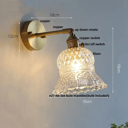 Antique brass-finished wall light fixture with faceted clear glass bell-shaped shade and amber flower crystal design