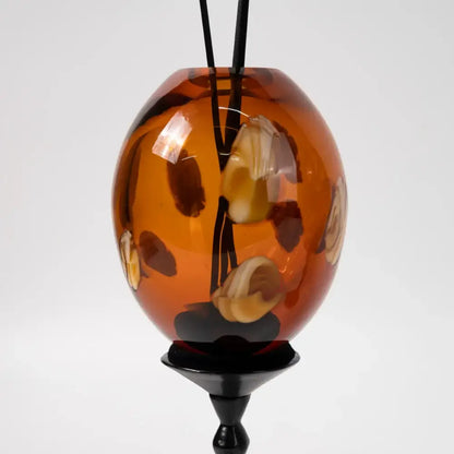 Amber geometric circle glass pendant with natural stone inclusions suspended from black cord for living room decorbites geometric circle decor