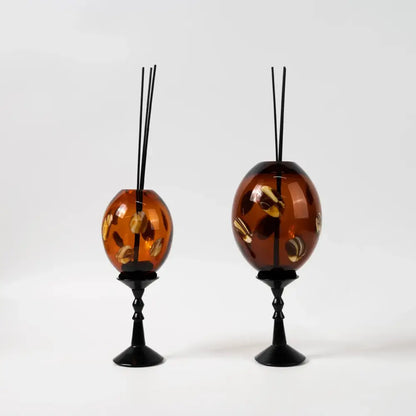 Amber geometric circle glass reed diffuser holders with gold-leaf shell inlays on black metal stands for living room decor