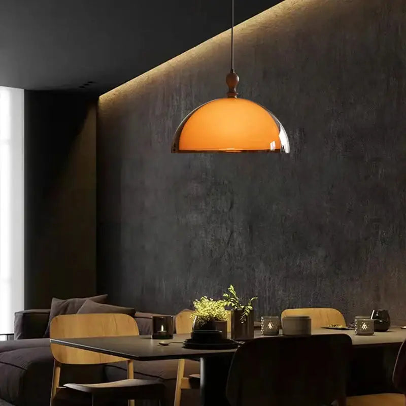 Warm amber glass pendant light with dark wood accent and polished metal rim for dining room lighting