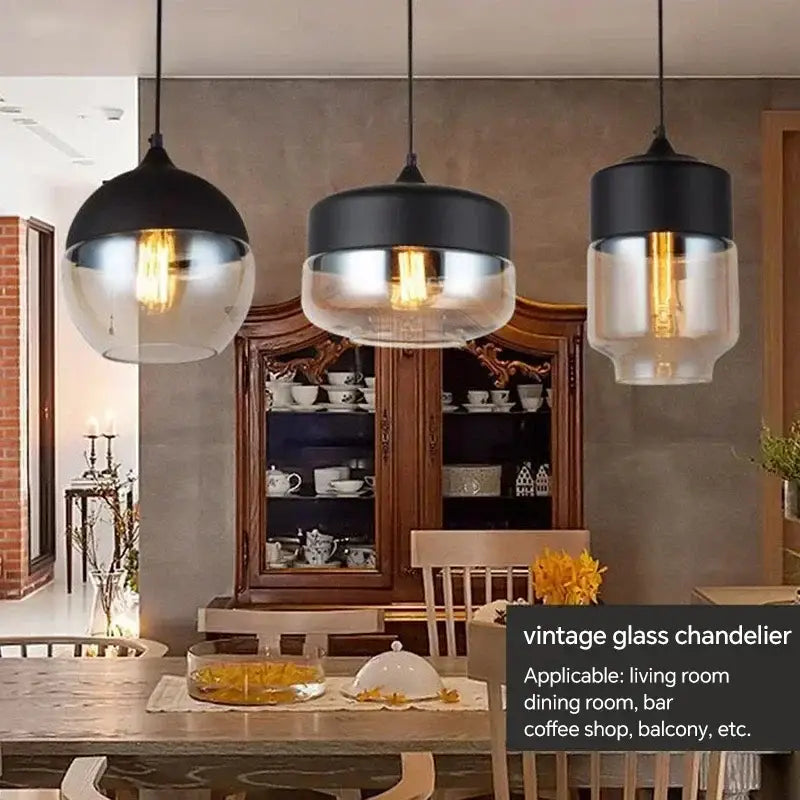 Three black and clear amber glass pendant light fixtures with exposed filament bulbs hang above a dining table