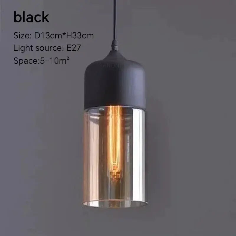 Black pendant light fixture with cylindrical glass shade and exposed Edison bulb for dining room lighting