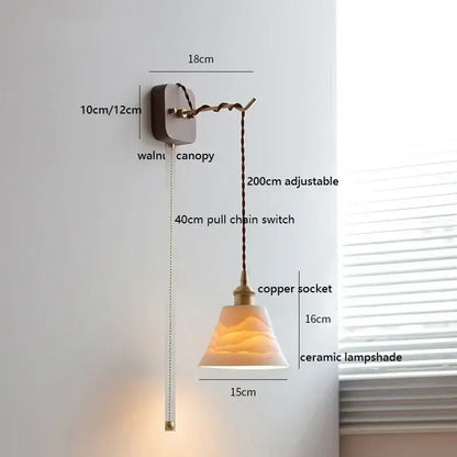 A warm-toned amber ceramic ball led wall light with textured surface and pull chain on walnut canopy by decorbites ceramic ball