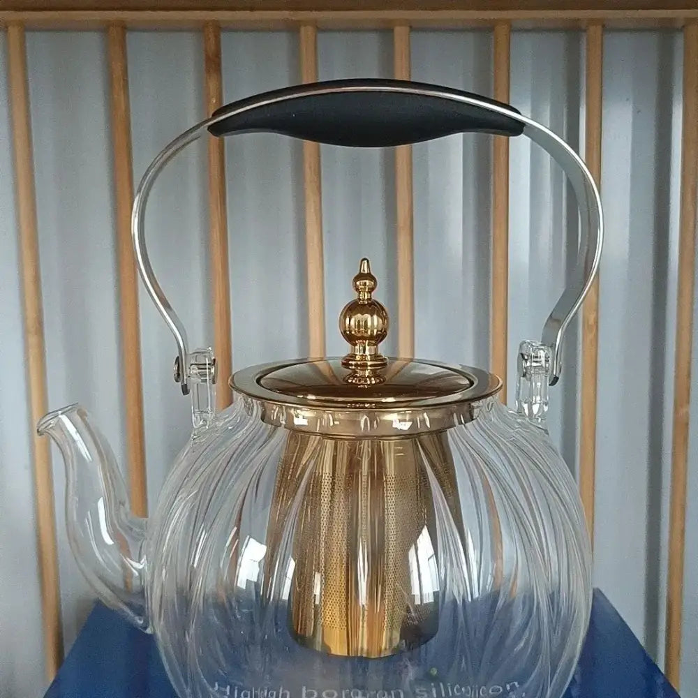 Clear glass teapot with gold-toned lid handle spout and golden mesh infuser from decorbites amber glass teapot collection