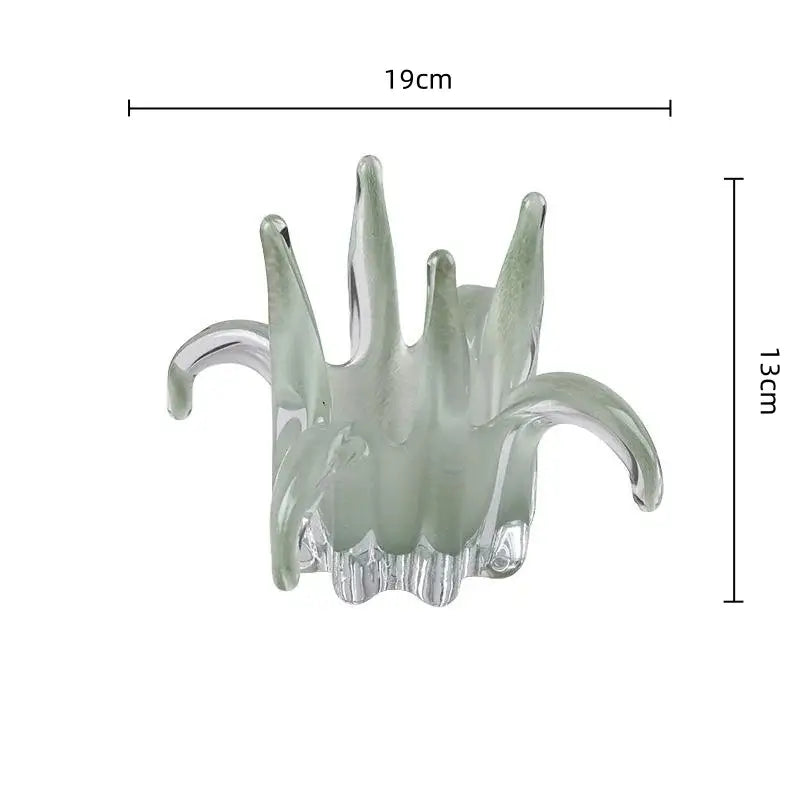 A translucent green glass petal candle holder shaped like a hand with curved finger-like extensions for living room decor