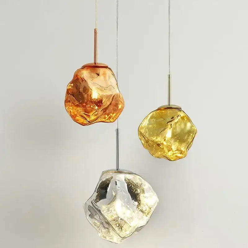 Three hanging amber gold and clear decorbites ice glass pendant lights with organic shapes for dining room decor