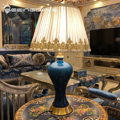 Deep blue ceramic table lamp with gold accents and a cream pleated shade for decorbites American luxury bedroom decor