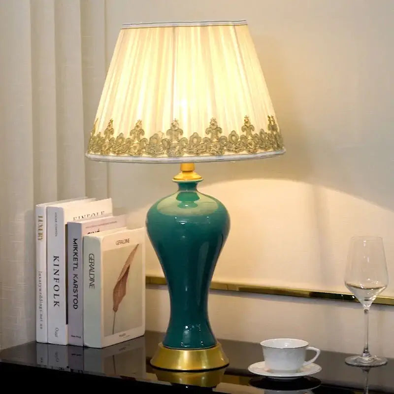 Teal ceramic table lamp with gold accents and cream pleated shade featuring ornate gold trim by decorbites american luxury