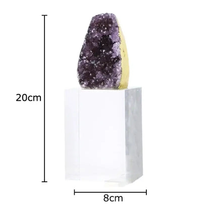 A striking purple amethyst crystal base geode with a golden base displayed as a desk ornament on a clear acrylic pedestal
