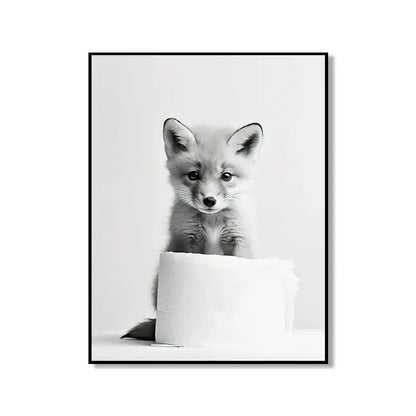 Black-and-white framed DecorBites bathroom wall art featuring a curious fox pup peeking over a toilet paper roll cute animal canvas