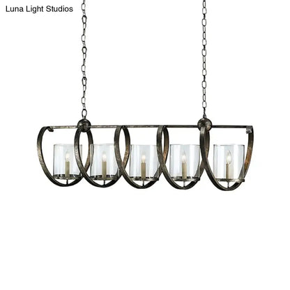 Antique brass dining room chandelier with five clear glass candle holders and lit white taper candles in bronze finish