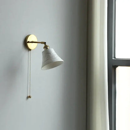A white marble-finish ceramic led wall light with a gold-toned metal arm and pull chain for elegant bedroom decorbites wall light