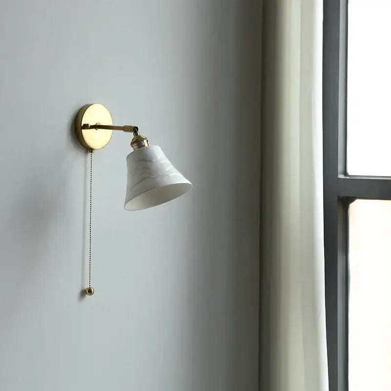 A white marble-finish ceramic led wall light with a gold-toned metal arm and pull chain for elegant bedroom decorbites wall light