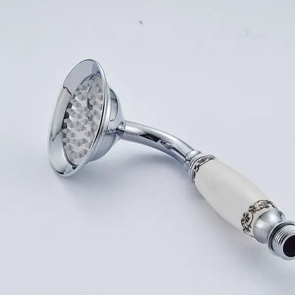 Antique brass and chrome hand shower head with chrome finish and cream ceramic handle featuring black floral patterns