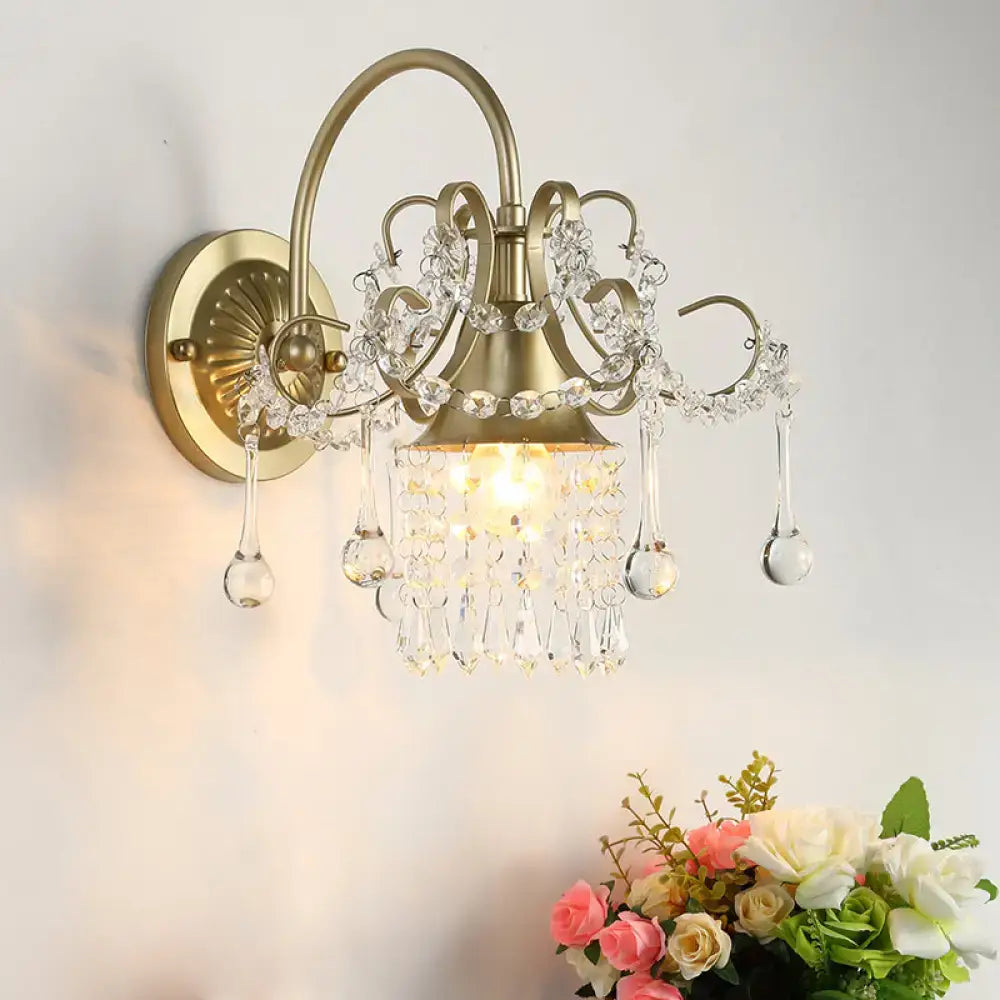 Antique brass wall light sconce with crystal teardrop accents and intricate filigree detailing for bedroom use