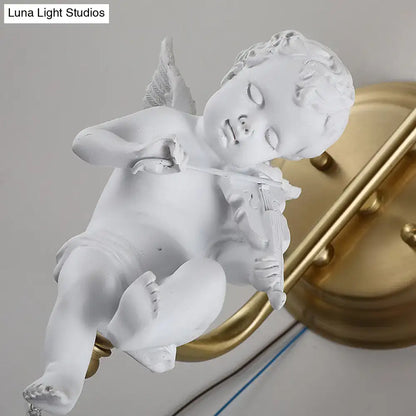 White angel figurine with delicate wings holding a violin as part of an antique brass glass sconce light for bedroom wall