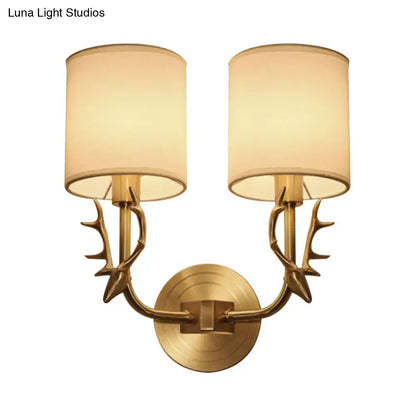 Antique brass antler wall sconce with fabric shade featuring a stylish design and two beige cylindrical shades for bedroom light