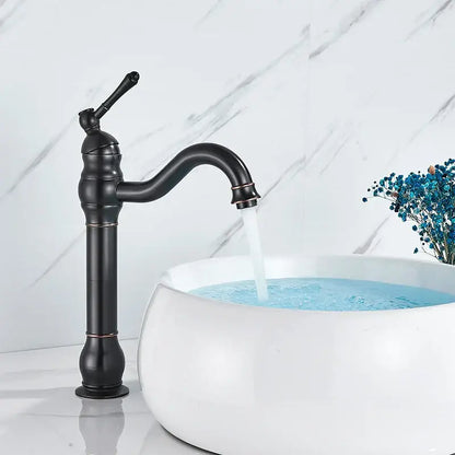 Black matte decorbites brass basin faucet with curved spout and ornate detailing beside white ceramic sink