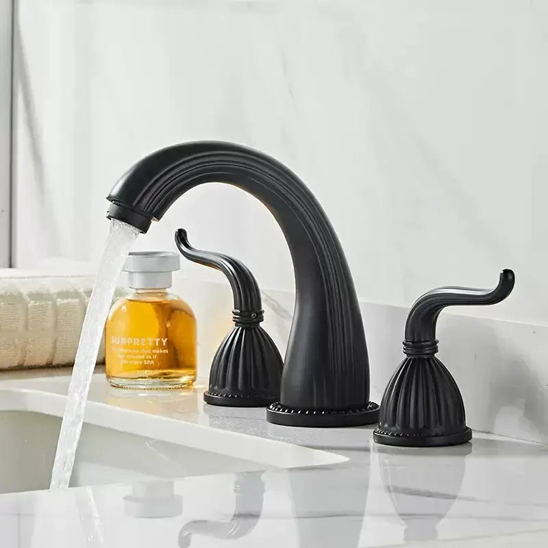 Black matte finished three-handle faucet set with curved spout and fluted handles in antique brass bathroom style