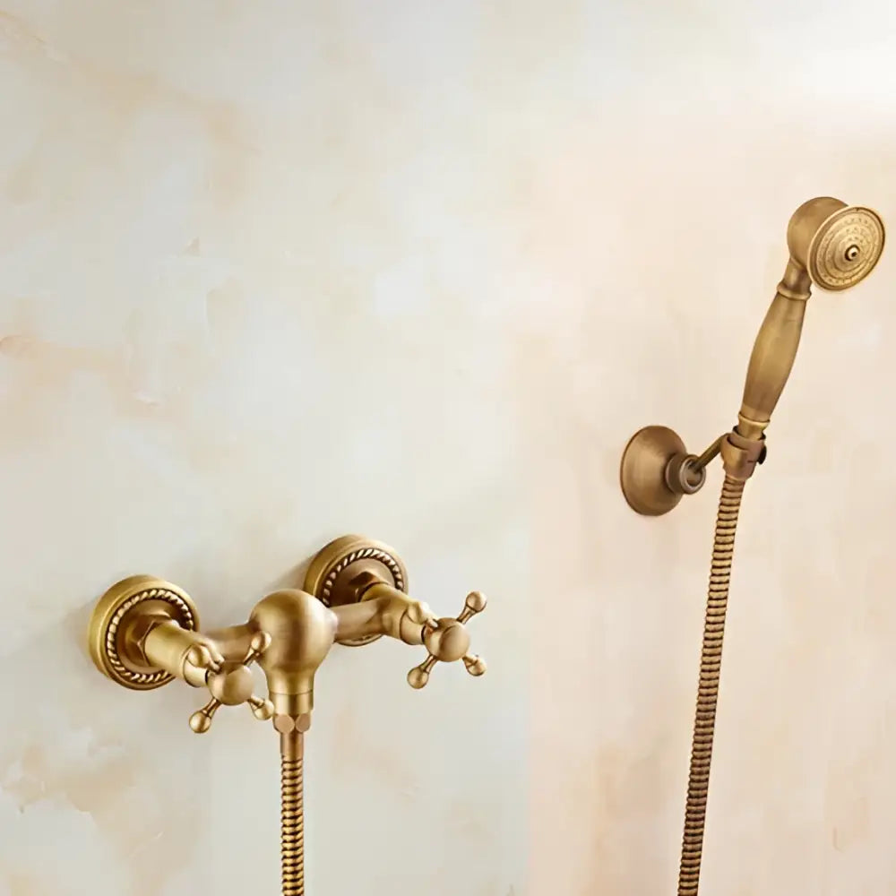 Antique brass bidet mixer faucet with ornate cross handles and matching handheld showerhead for bathroom use
