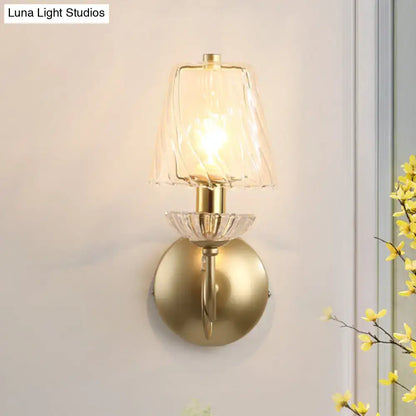 Antique brass conical sconce light with clear twisted glass shade and crystal accents for bedroom wall lighting