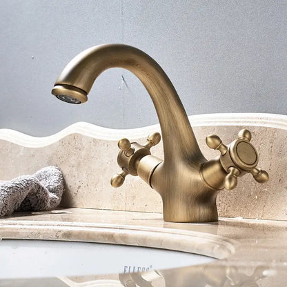 Antique brass dual handle basin faucet with vintage curved spout and ornate cross handles for bathroom vanity sink