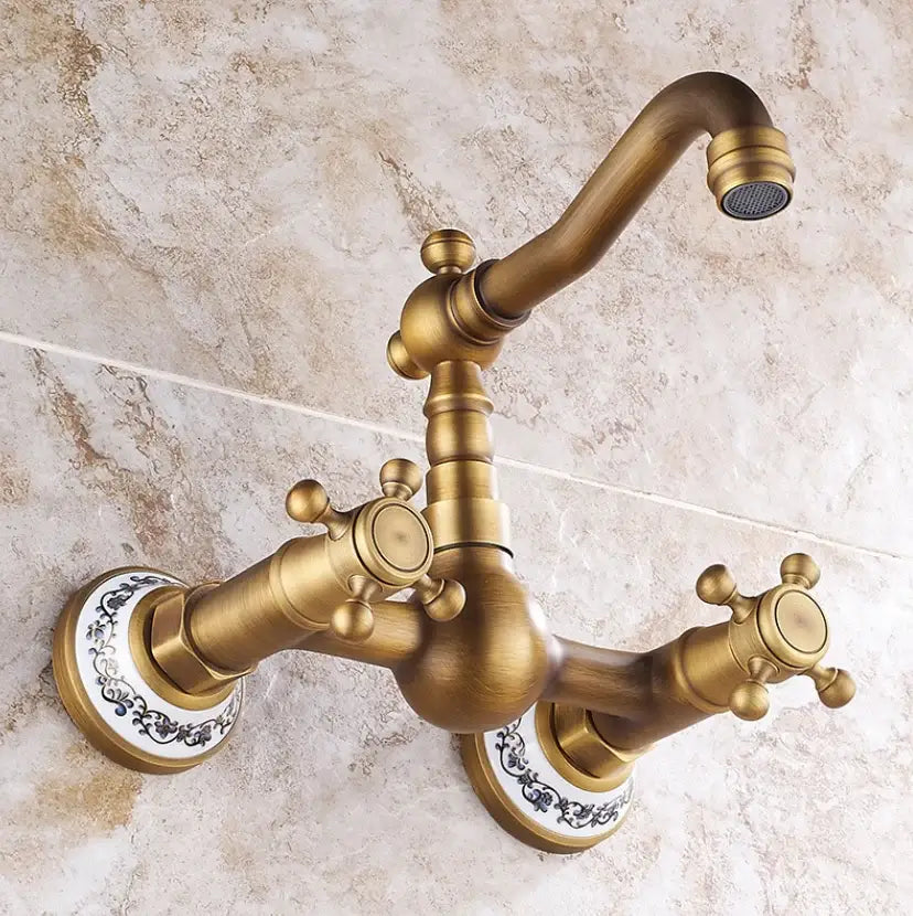 Antique brass dual handle kitchen faucet with hot water control and ornate porcelain plate wall-mounted design