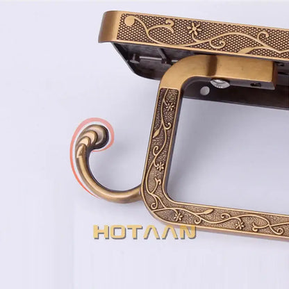 Antique brass toilet paper holder with floral and vine embossed metal frame and integrated phone rack for bathroom use