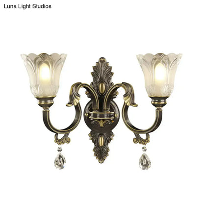 Antique brass floral wall sconce with metal base, two lights, frosted glass flower shades, and crystal pendants, inches tall
