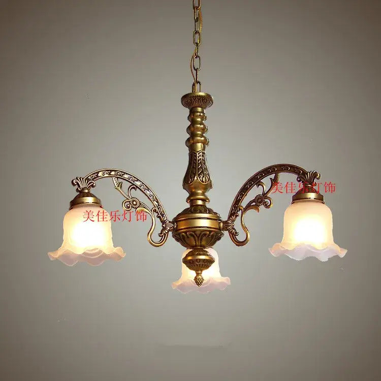 Antique brass three-arm shade ceiling chandelier with ornate scrollwork and frosted glass shades for dining room