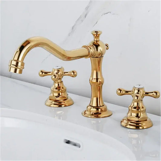 Antique brass gold finish bathroom sink faucet with ornate cross handles and a curved spout in gold finish