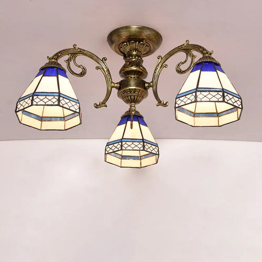 Antique brass three-arm semi flush mount ceiling fixture with blue and cream stained glass bell shades featuring geometric patterns