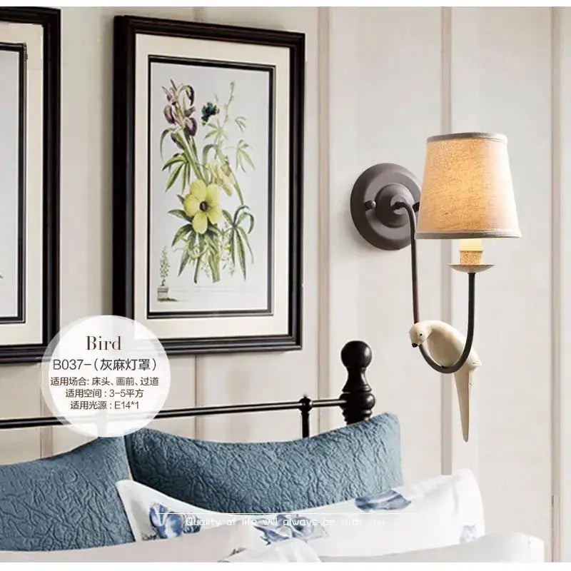 Antique bronze and cream ceramic bird wall lamp with beige fabric shade and dark metal arm for bedroom decorbites bird decor