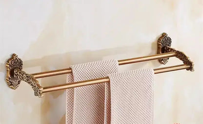 Antique brass double towel rack with ornate scrollwork ends holding beige towels in decorbites bronze carved bath set