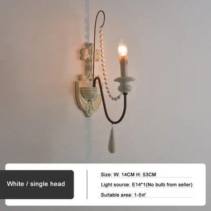 White single-head country french wall lamp with ornate floral design black curved arm and beaded chain decorbites country french