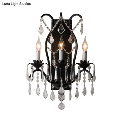 Black wrought iron candelabra wall light with three candle bulbs and cascading crystal droplets for dining room use
