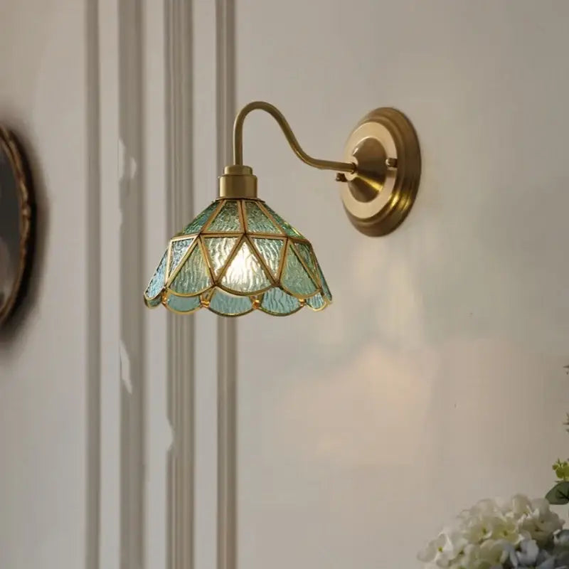 Antique teal glass and brass wall light fixture with tiffany-style stained glass shade in teal and gold for bedroom use