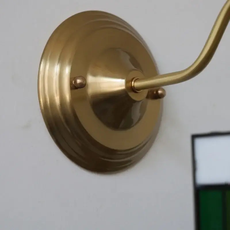 Antique teal glass and brass wall light fixture with circular base and curved arm for bedroom sconce use