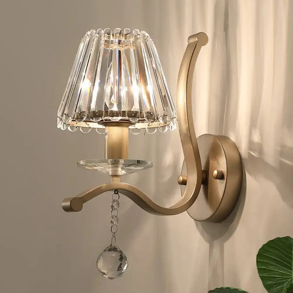 Antiqued gold wall mount light fixture with brass finish and cascading crystal prism shade for bedroom sconce use