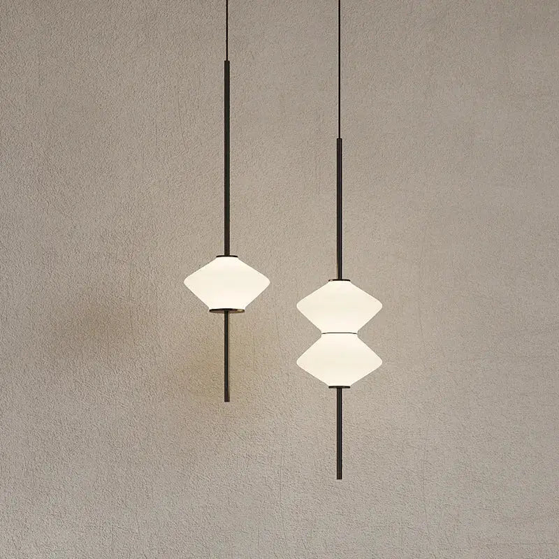 Two minimalist art deco pendant lights with black metal rods and white glass stacked diamond shades for dining room