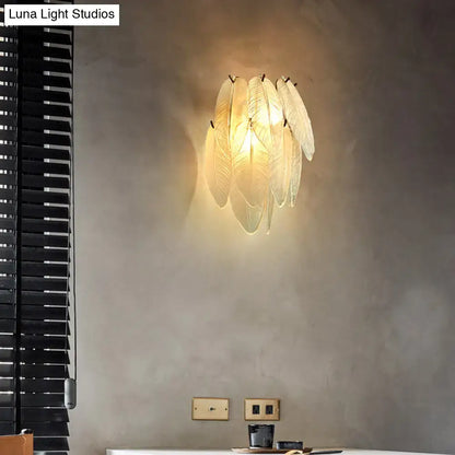 Art deco brass leaf sconce lamp with warm glowing clear glass feather-shaped shades for dining room lighting