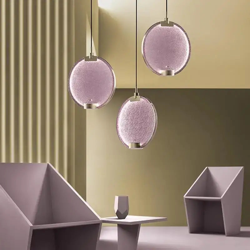 Three spherical lavender decorbites clear pink glass pendant lights with textured surface and metallic fixtures for kitchen