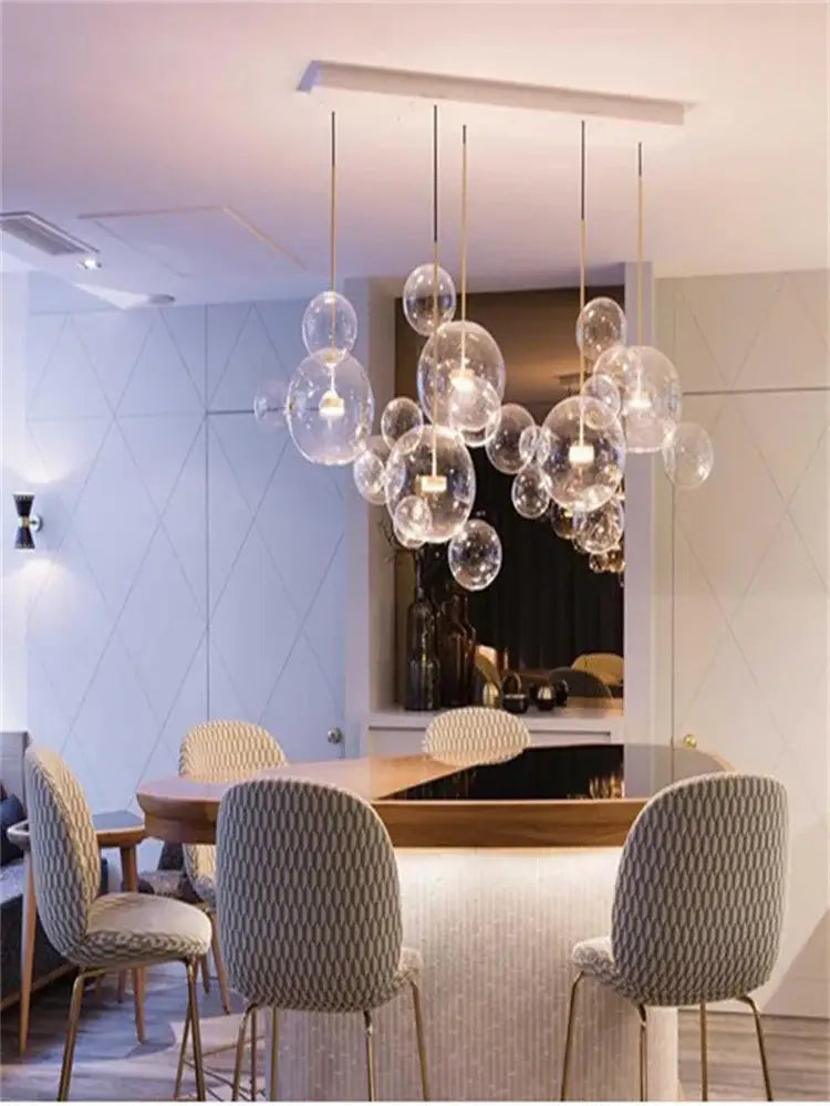 A modern art deco glass bubble chandelier with clear spherical bulbs and gold-toned rods for dining room decorbites