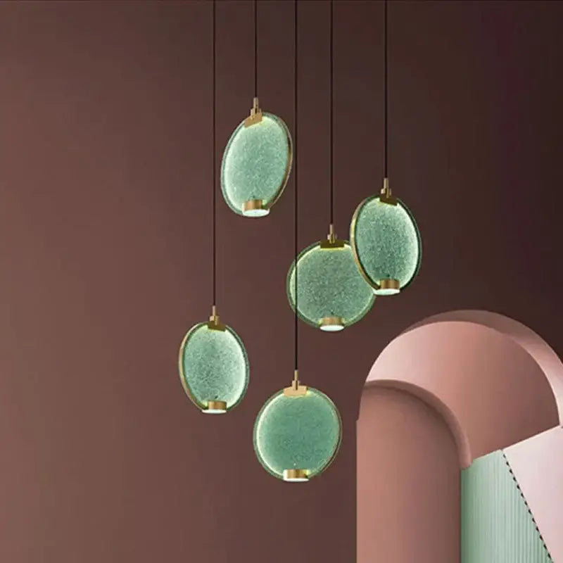 Five suspended oval pendant lights with textured green glass and gold fixtures in decorbites glass horo led style