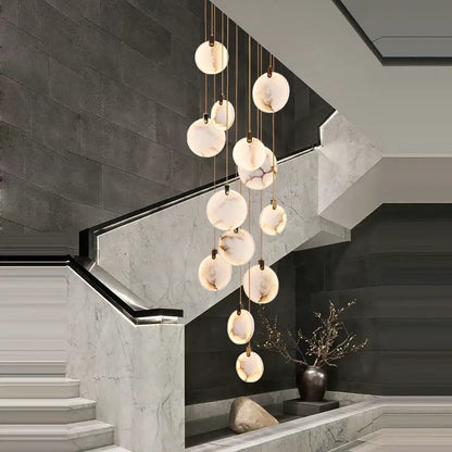 A modern art deco marble golden lustre pendant light with spherical translucent shades for dining rooms