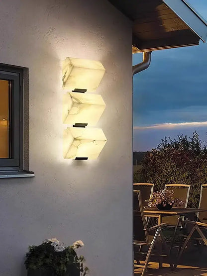 Modern three-light wall sconce with warm glowing white marble panels for decorbites art deco marble living room decor