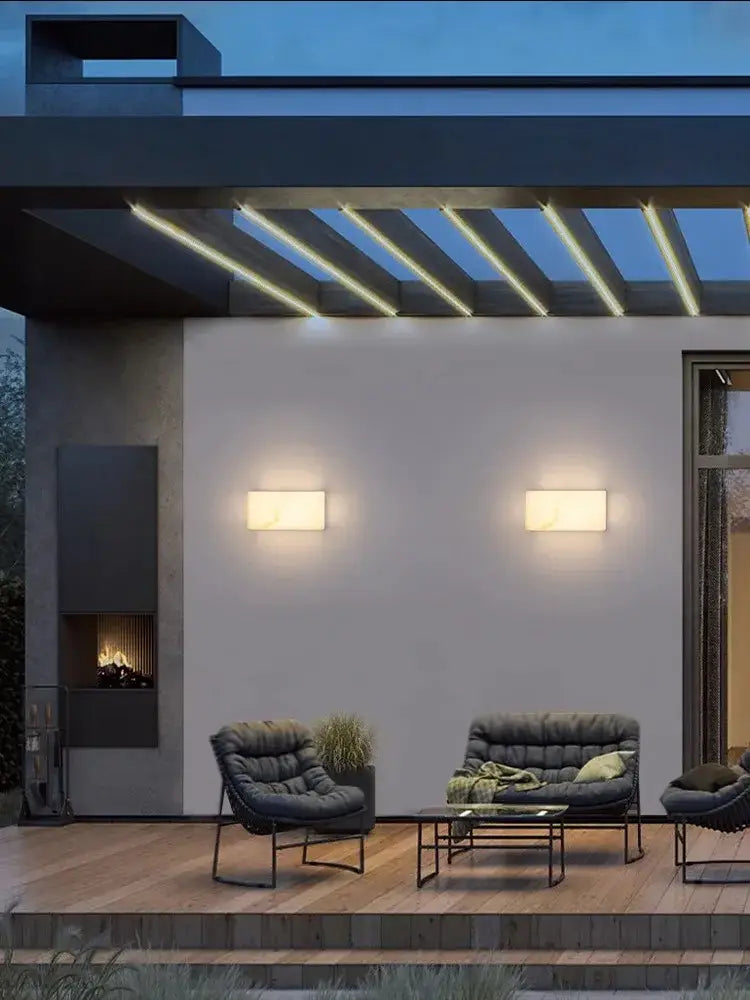 Modern black tufted outdoor sofa with sleek metal frame and green pillows shown with decorbites art deco marble wall sconce