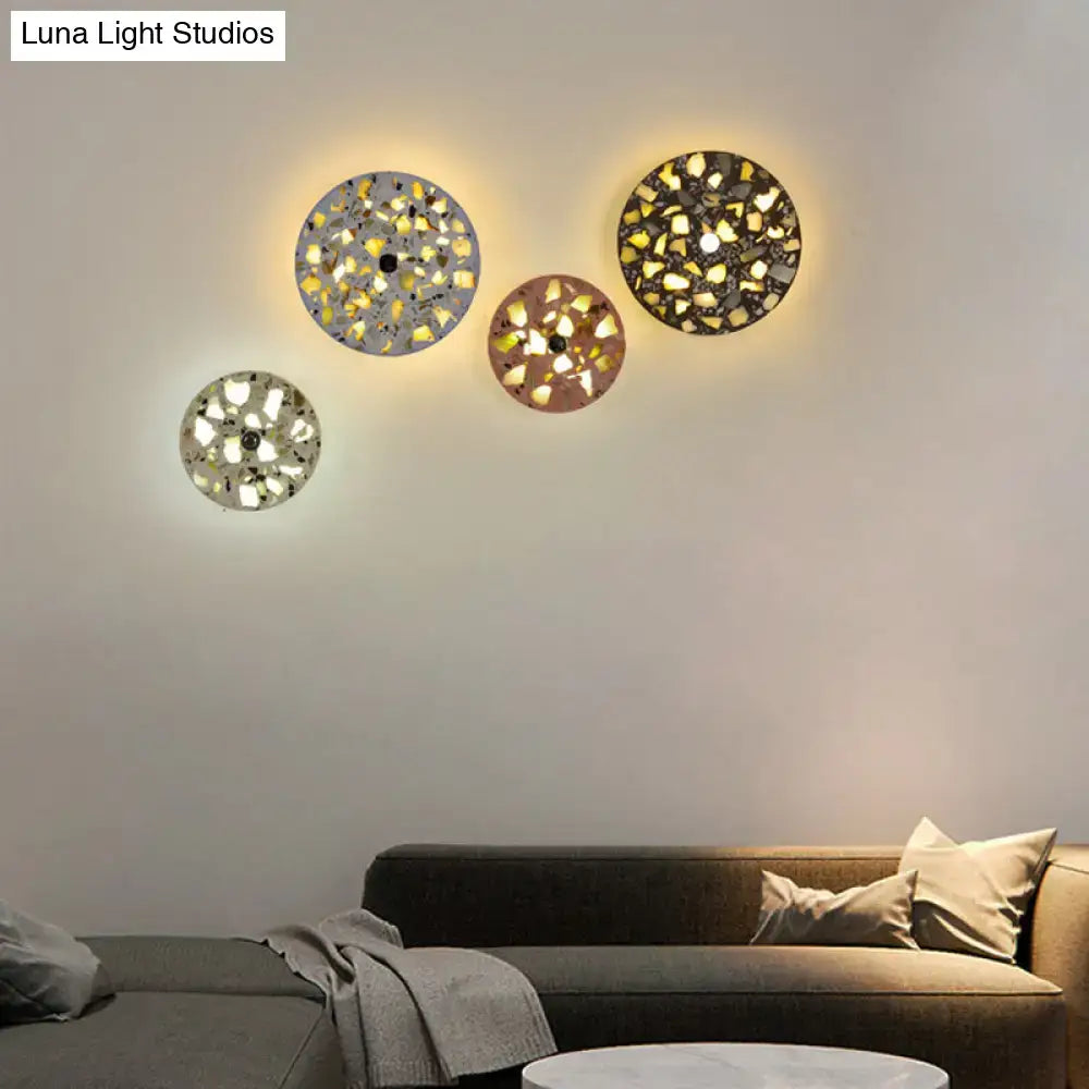 Three circular art deco mosaic terrazzo led wall sconces with metallic and translucent pieces emitting warm glow for living room