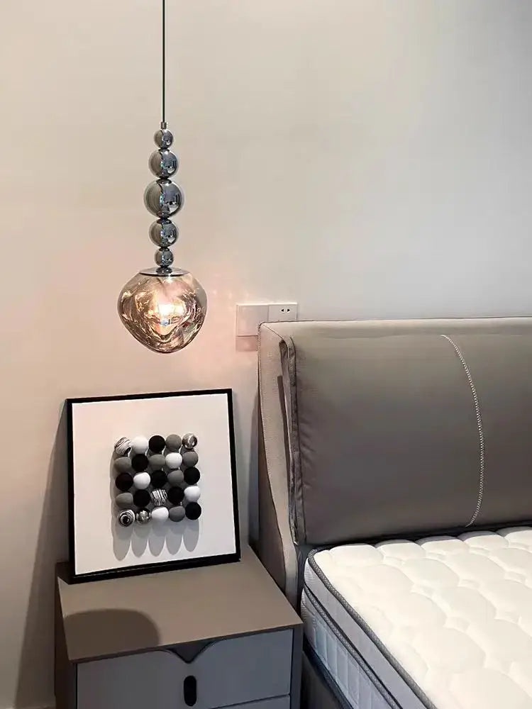 Art deco silver lava pendant light with polished silver spheres and led bulb hanging above bedside table