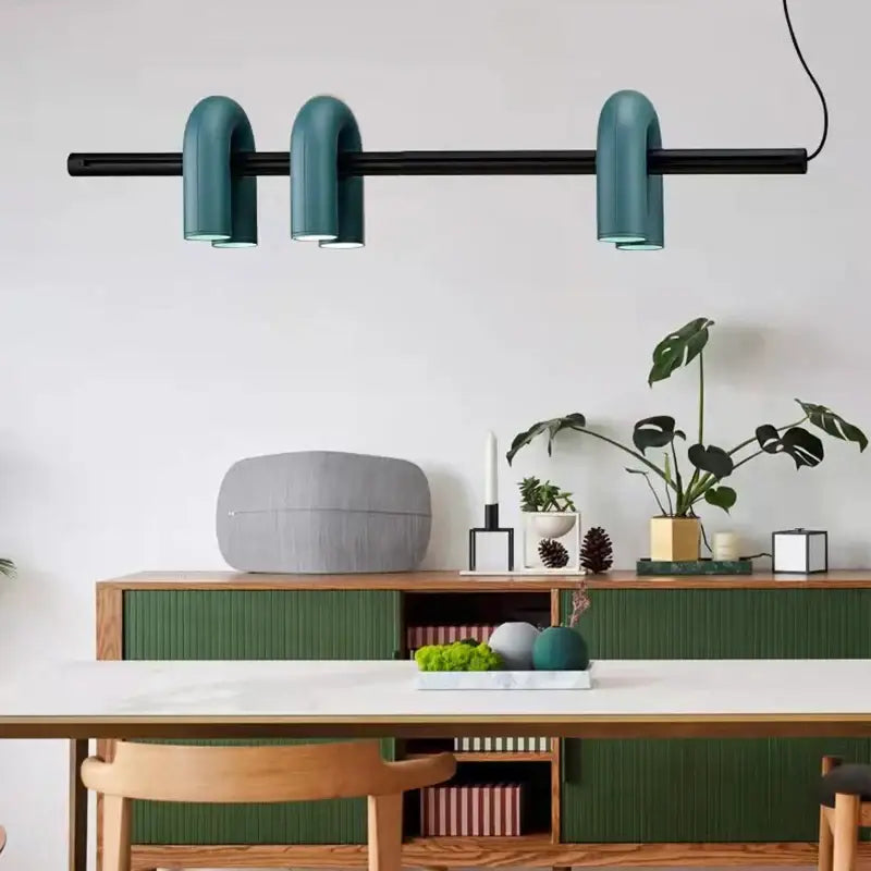 Art deco metal teal 3 light pendant with curved tubular shades suspended from a black bar for dining room decor